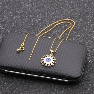 Dettaglio della collana occhio di Allah dorata con zirconi colorati su scatola per gioielli
