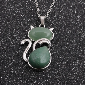 Collier chat en acier argenté avec pendentif en pierre verte sur fond noir étincelant