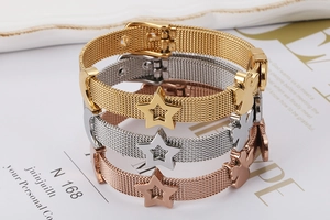 Dettaglio di bracciali in maglia di acciaio con ciondoli a stella e angelo in tre colori