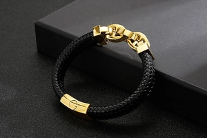 Close-up of black braided leather bracelet featuring a gold G-engraved metal buckle