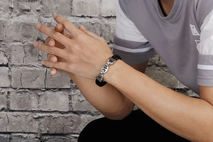 Detail of men's black woven leather bracelet with silver pig nose steel clasp on wrist