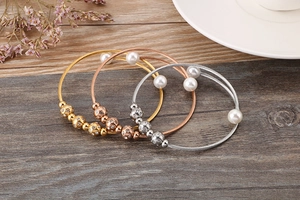 Stack of gold, rose gold and silver wire cable bangles with pearls and crystals