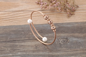 Macro detail of rose gold open coil bracelet with white pearls and pave crystal spheres