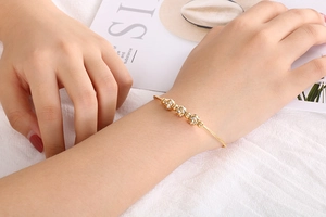Detail of a gold titanium steel bracelet with four zircon beads on a woman's wrist