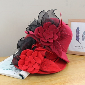 Detail of red wool felt pillbox hat featuring mesh veil, flowers and feathers
