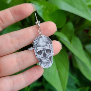 Detailansicht des Totenkopf-Ohrrings mit Kappe vor einem grünen Blatthintergrund