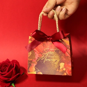 Close-up of red and gold floral wedding gift bag with a Sweet Memory bow and gold rope
