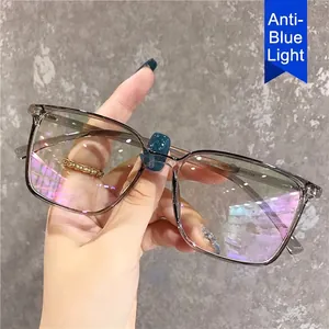 Square anti-blue light glasses with transparent grey frame in a lifestyle hand-held shot