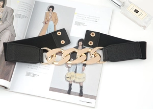 Détail d'une ceinture élastique noire avec boucle chaîne dorée et fermeture à pression