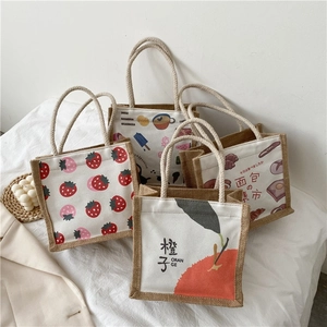 Detailed view of canvas lunch bags with strawberry and orange prints and cotton rope handles