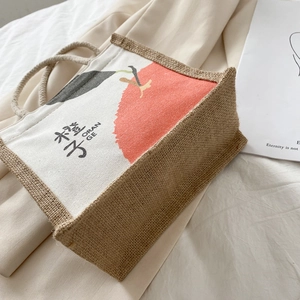 Canvas and jute tote bag with orange print and rope handles on minimalist beige fabric