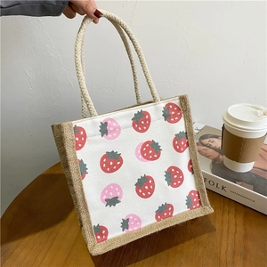 Detail of canvas bento bag featuring jute texture and cute strawberry print on wooden table