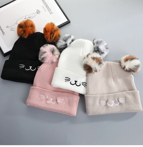 Detail of four knit cat ear beanies in black pink white beige with pom poms and embroidery