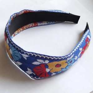 Close-up of floral embroidery on wide knotted headband with ethnic patterns