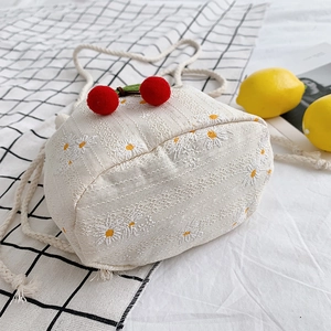 Off-white canvas bucket bag with daisy embroidery and cherry pom-pom drawstrings