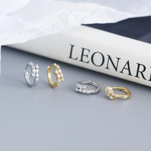 Detail of floral zircon earrings in gold and silver finish with sparkling stones