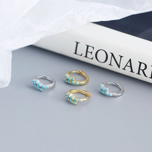 Macro shot of gold and silver S925 sterling silver hoop earrings with blue turquoise inlay