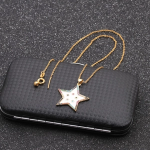 Macro detail of gold star pendant necklace featuring multicolored gemstones on a black box