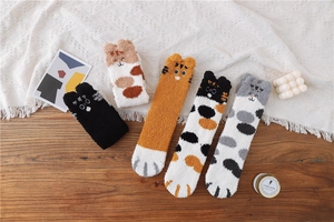 Flat lay of fluffy coral fleece animal socks with cat paw patterns on a cozy wooden table