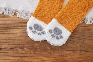Close-up of soft coral fleece cat paw socks in ginger yellow and white plush material