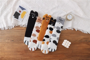 Flat lay of five cute cat-themed coral fleece socks on a cozy knit blanket background