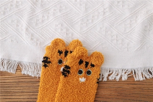 Detailed texture of fluffy orange tiger cartoon socks in soft coral fleece fabric