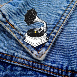 Spilla smaltata a forma di grammofono con galassia e astronauta su giacca denim