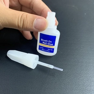 Detail of 10g brush-on nail glue bottle with applicator brush on textured surface