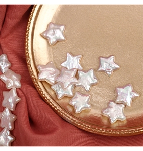 Macro shot of iridescent star-shaped freshwater pearl beads on a golden plate