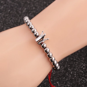 Silver beaded crown charm bracelet displayed on a model wrist with a dark background