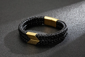 Close-up of double-layer black woven leather bracelet with golden arrow magnetic clasp