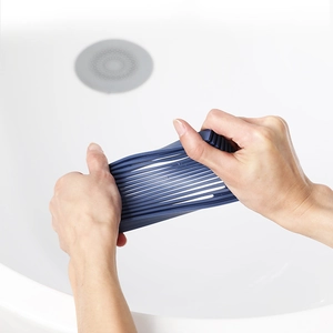 Blue silicone hair catcher drain protector shown being stretched for flexibility