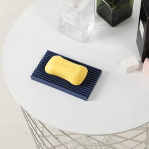 Deep blue silicone soap dish with drainage slats on a minimalist white bathroom tray