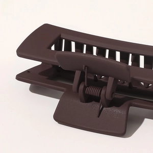 Macro view of a large chocolate brown matte claw clip with strong metal spring detail