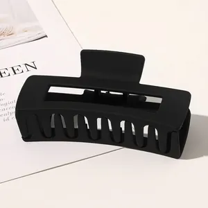 Detailed view of a large black matte rectangular hair claw clip on a minimalist background