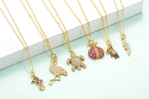 Close-up of golden ostrich and flamingo pendants with colorful sparkling zircons