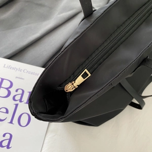 Minimalist black tote bag featuring a high-quality gold zipper and durable nylon texture