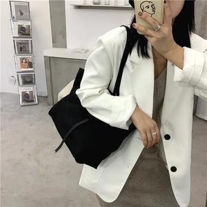 Minimalist black large tote bag shown on shoulder with stylish draped silhouette