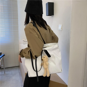 Minimalist white large tote bag with black shoulder strap and brown teddy bear pendant