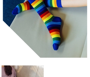 Detail of colorful rainbow striped knee high socks shown on a model sitting on a sofa