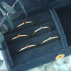 Set of five minimalist gold rings with vibrant colored zircons in a navy velvet box