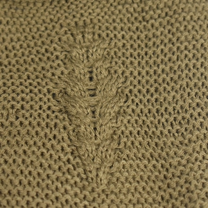 Detailed macro view of moss green knitted winter hat showing embossed leaf texture pattern