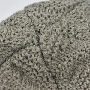 Close-up of thick grey knit texture showing detailed V-shaped stitching on winter hat