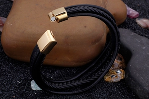 Detail of multi-layer braided leather bracelet with golden magnetic clasp on stone