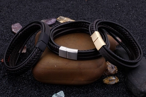 Detail of multi-layer braided leather bracelets with black, silver, and gold magnetic clasps