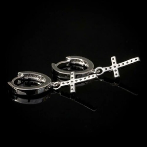 Detail view of silver cross hoop earrings with shimmering pave zircon inlay on black surface