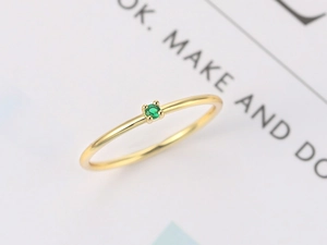 Macro detail of minimalist gold-plated ring with a four-prong set green zircon stone