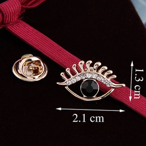 Macro shot of eye-shaped gold brooch with black crystal and rhinestones on velvet
