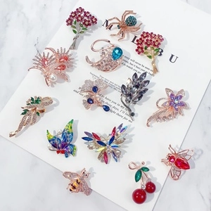 Vue détaillée de broches fleurs et insectes en strass colorés sur cartes de présentation