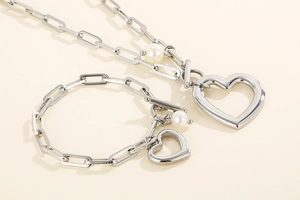 Détail du parure de bijoux en acier inoxydable argenté avec grosse chaîne et charms en cœur